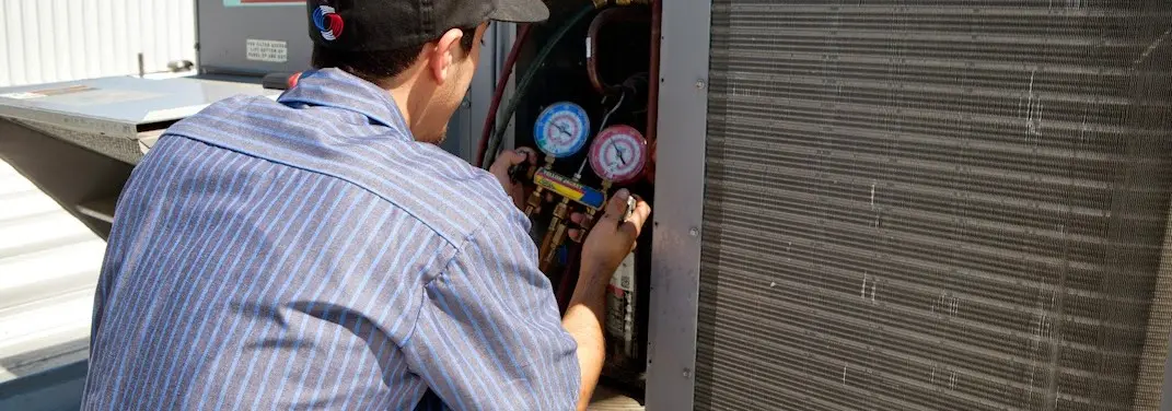 HVAC technician servicing a condenser unit in Malta
